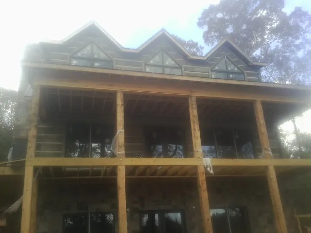 Dormers and porch framing on a large log home under construction — Roof Coating work by our crew in Mead