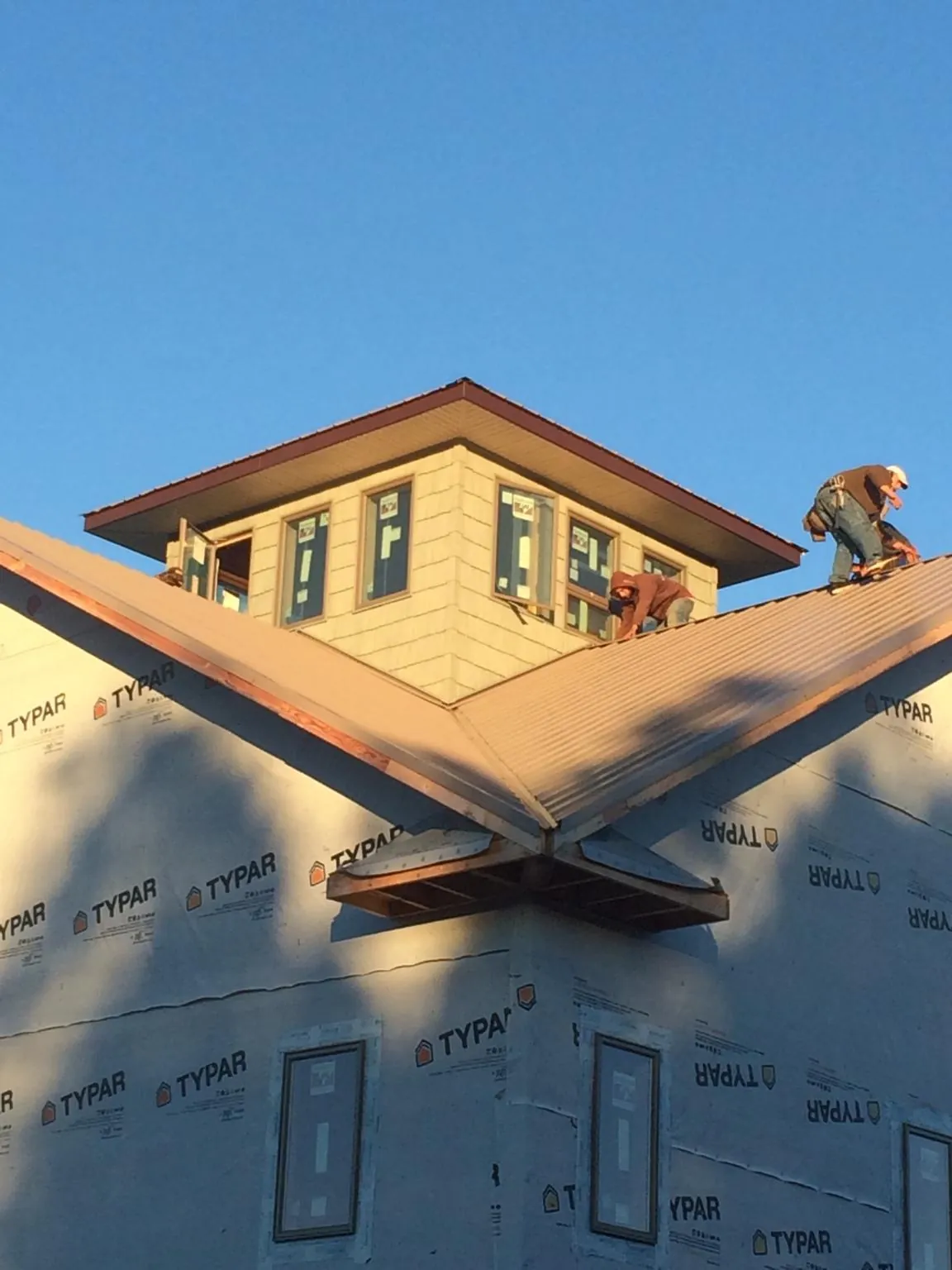 Roofers working around a rooftop cupola on a new metal roof at sunset — Roof Waterproofing in Mead by Roofing Brothers